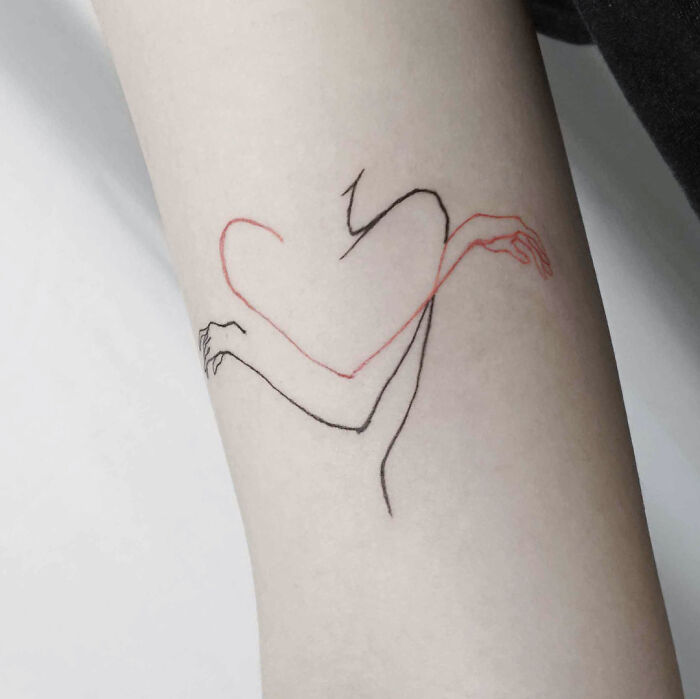 Minimalist tattoo of red and black lines forming a heart with intertwined arms on skin.