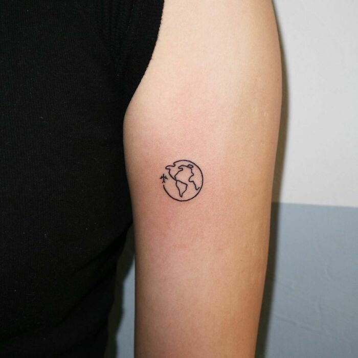 Simple first tattoo of a minimalist globe design on an arm.
