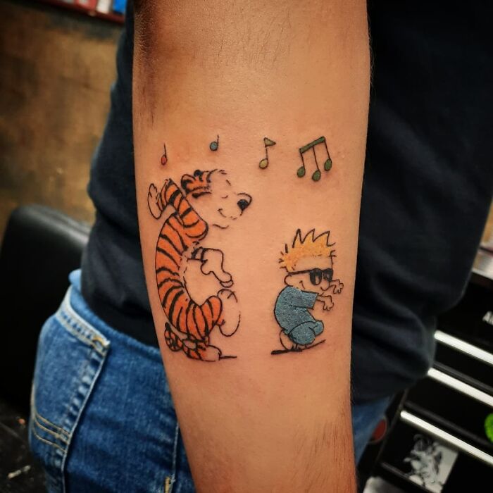 Anime characters dancing in a colorful first tattoo design with musical notes, on a person's forearm.