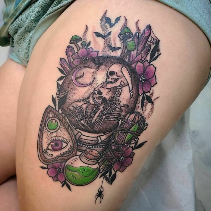 Spooky Halloween tattoo featuring a skeleton, flowers, crystals, and an eye with the message "Hello Goodbye".