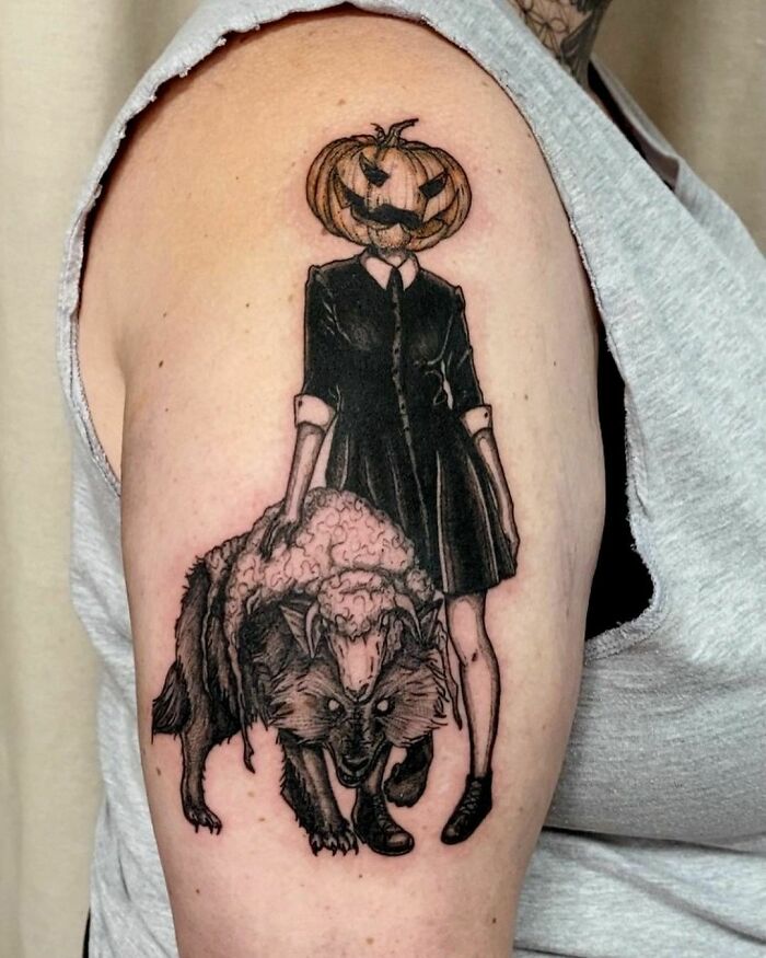 Tattoo of a person with a pumpkin head holding a wolf, creatively capturing spooky Halloween themes for horror lovers.