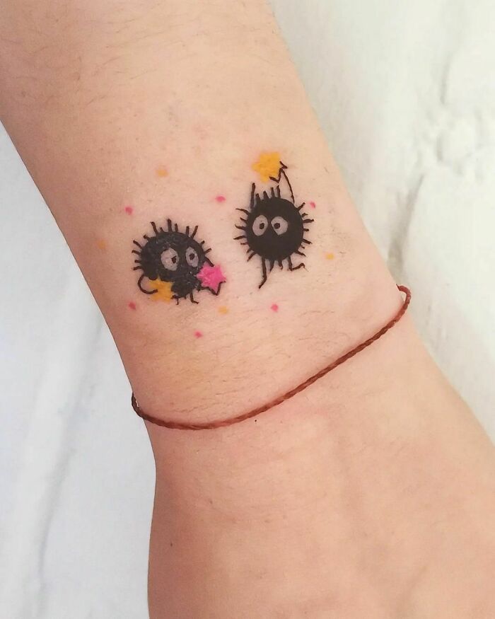 Cute soot sprites tattoo with colorful stars on a wrist, showcasing interesting first tattoo ideas.