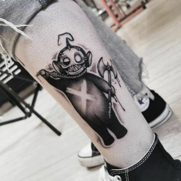 Spooky Halloween tattoo featuring a creepy character with an axe on a person's leg, showcasing brilliant horror art.