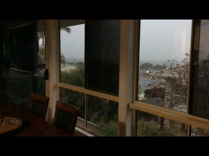View from a window showing rainy and foggy weather outside during September with trees and rooftops visible.