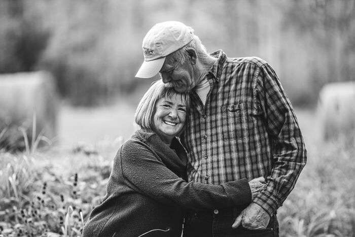 Elderly couple in love embracing outdoors, smiling warmly during a candid photo capturing couples in love.