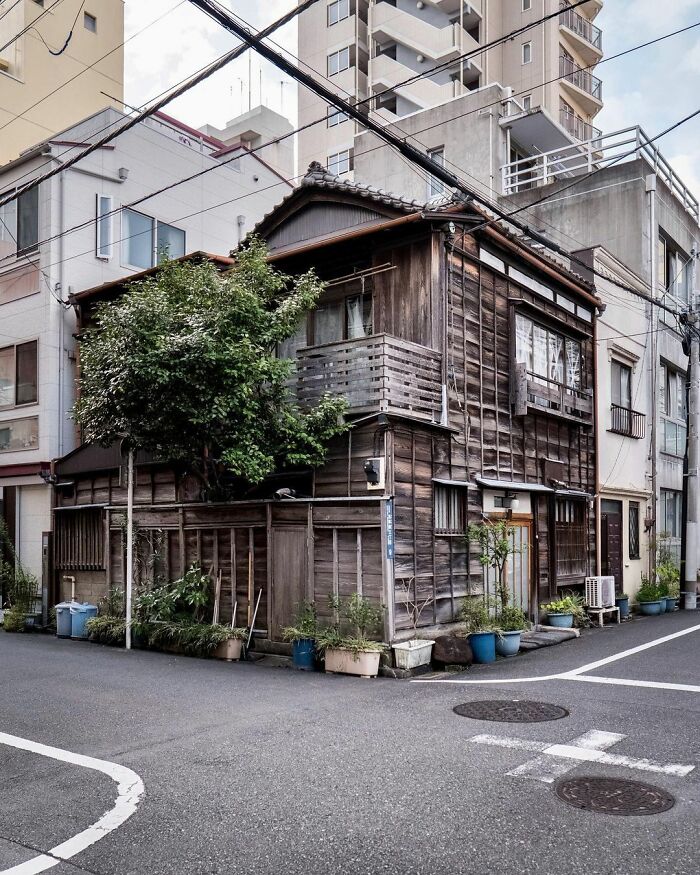 Traditional old architecture in Japan with wooden exterior, set against modern buildings in an urban neighborhood.