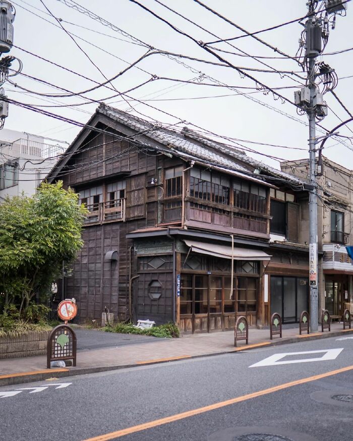 Old Japanese wooden architecture on a street corner showcasing traditional design amidst modern urban elements.