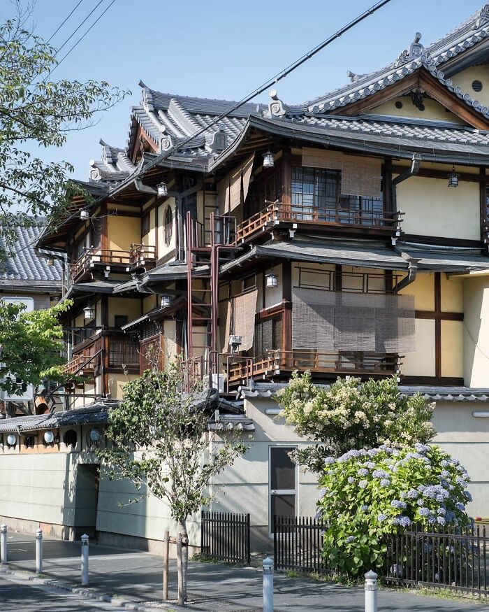 Traditional old architecture in Japan with wooden details and tiled roofs blending with modern surroundings and greenery.