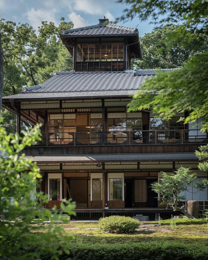 Traditional old architecture in Japan featuring wooden design, sliding doors, and a serene garden setting under clear skies.