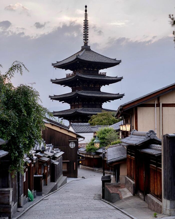 Traditional old architecture in Japan featuring a historic pagoda and wooden houses along a quiet street at dusk.