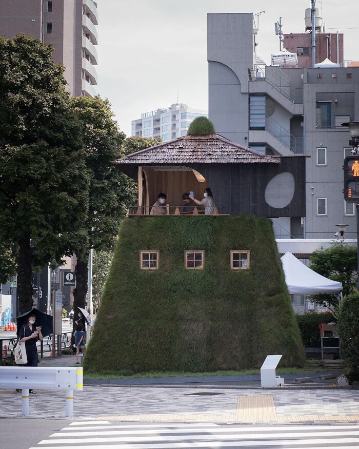 Traditional Japanese old architecture with a grass-covered base and wooden upper structure set in an urban environment.