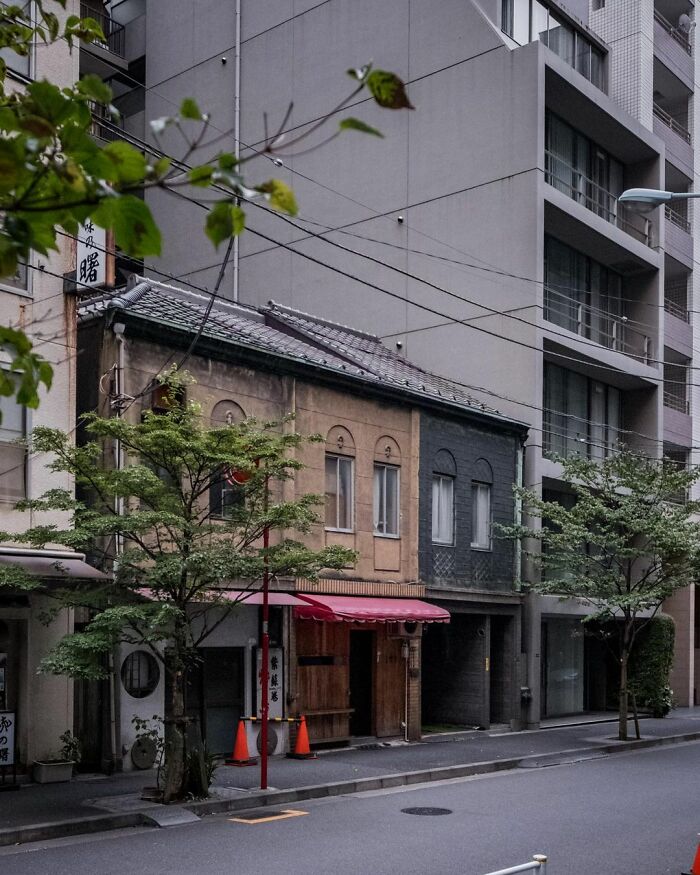 Old architecture in Japan with traditional buildings standing beside modern high-rise apartments on a quiet street.