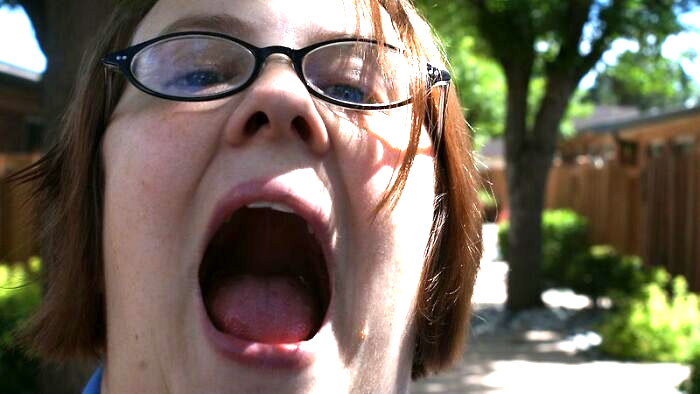 Close-up of a person with glasses outdoors in bright sunlight, capturing a candid moment in an online group discussion.