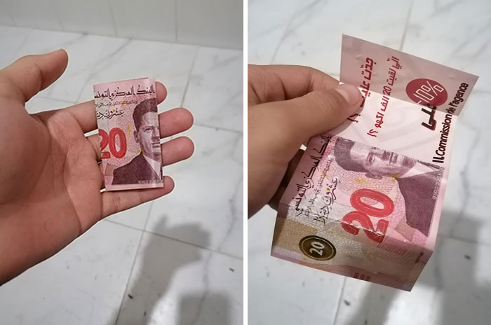 Hand holding a folded 20 currency note with hidden promotional message, illustrating evil marketing techniques.
