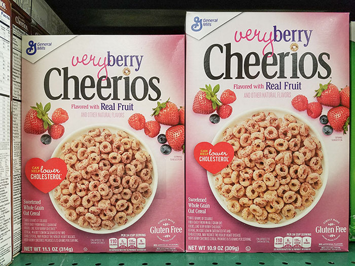 Boxes of Very Berry Cheerios cereal displayed on a store shelf, highlighting marketing techniques and product labeling.