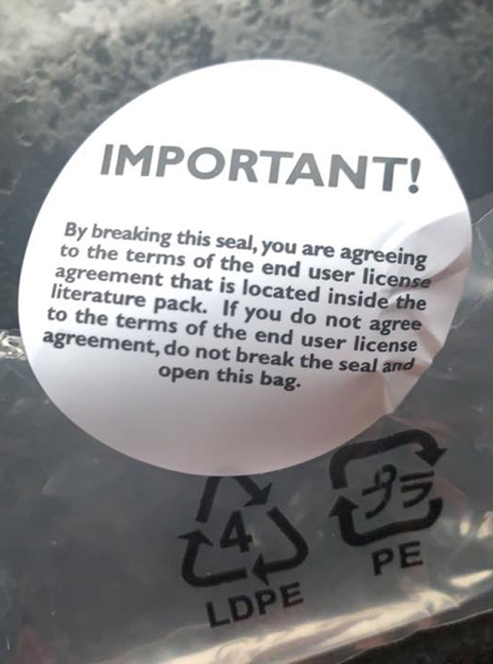 Seal on plastic bag warning users they agree to end user license terms by breaking it, showcasing evil marketing techniques.