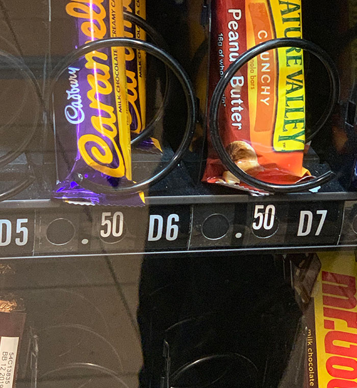 Candy bars displayed behind clear glass in a vending machine, illustrating evil marketing techniques in product placement.