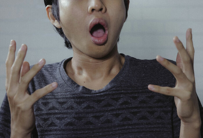 Young man expressing shock with open mouth and raised hands, illustrating disturbing facts that could ruin your day.