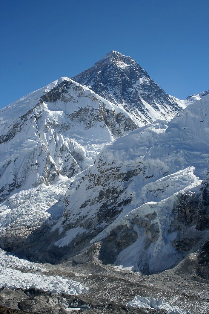 Snow-covered mountain peak under clear blue sky, illustrating nature's power alongside disturbing facts to ruin your day.