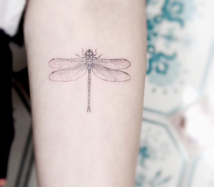 Intricate first tattoo idea featuring a detailed dragonfly design on the arm.