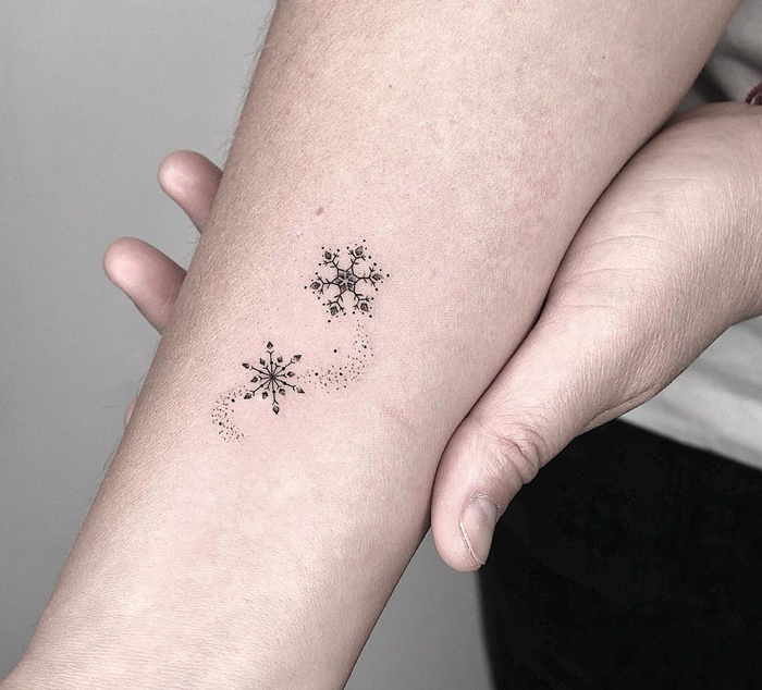 Intricate snowflake tattoo on forearm, showcasing a unique first tattoo idea.