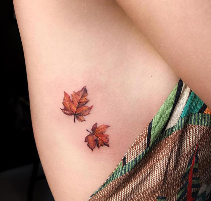 First tattoo idea featuring two intricate, realistic autumn leaves on skin.