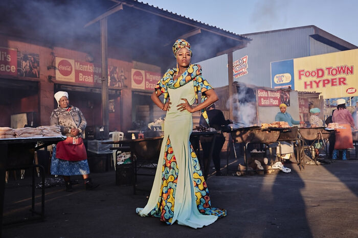Woman in colorful dress posing confidently at an outdoor market, showcasing powerful imagery from Siena International Photo Awards.