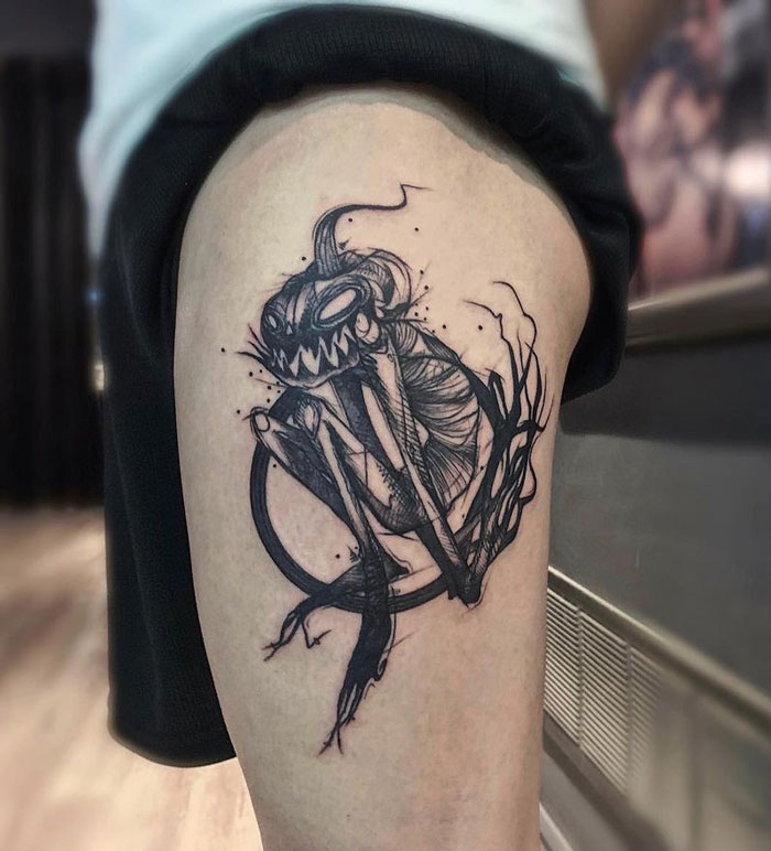 Spooky Halloween tattoo on upper thigh featuring a sinister creature in ink.