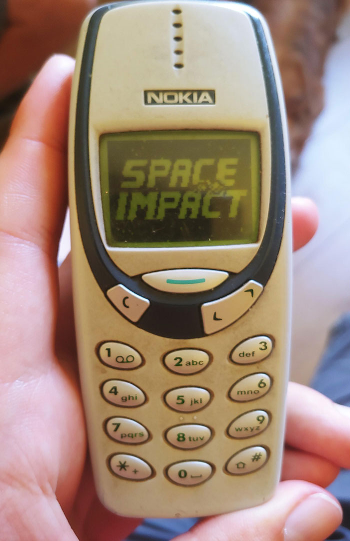 Nostalgic 2000s Nokia phone displaying Space Impact game screen.