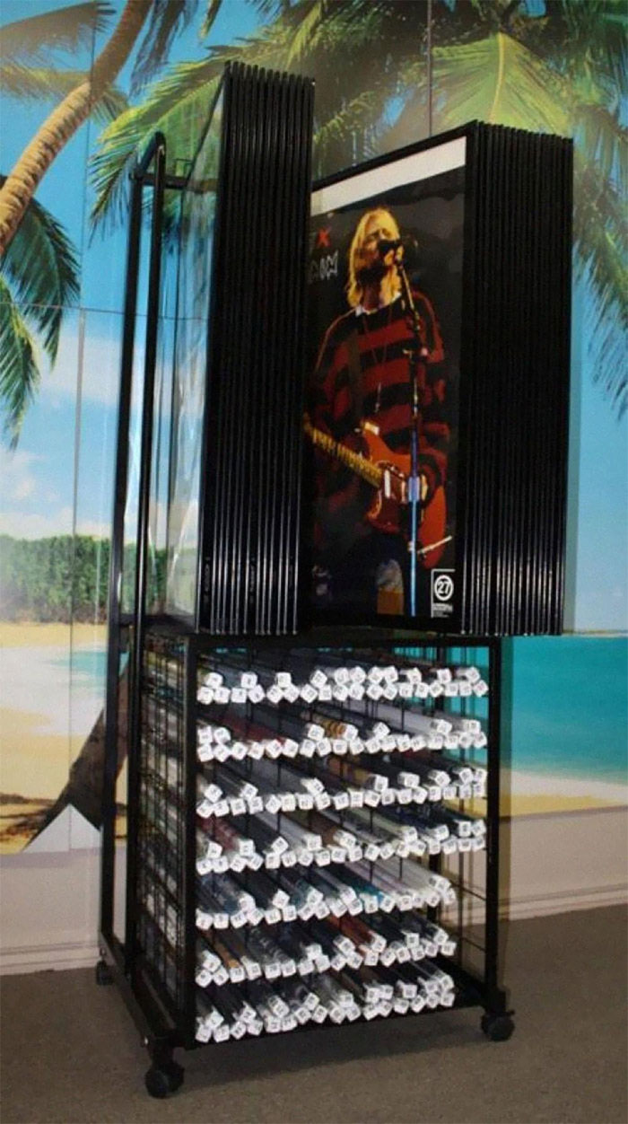 CD display rack filled with music CDs and a poster of a musician, capturing nostalgic memories from the 2000s.