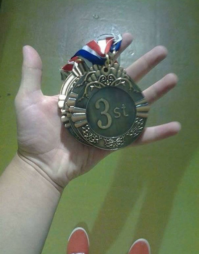 Hand holding a medal labeled "3st" with a colorful ribbon, humor reminiscent of memes about drinking water.