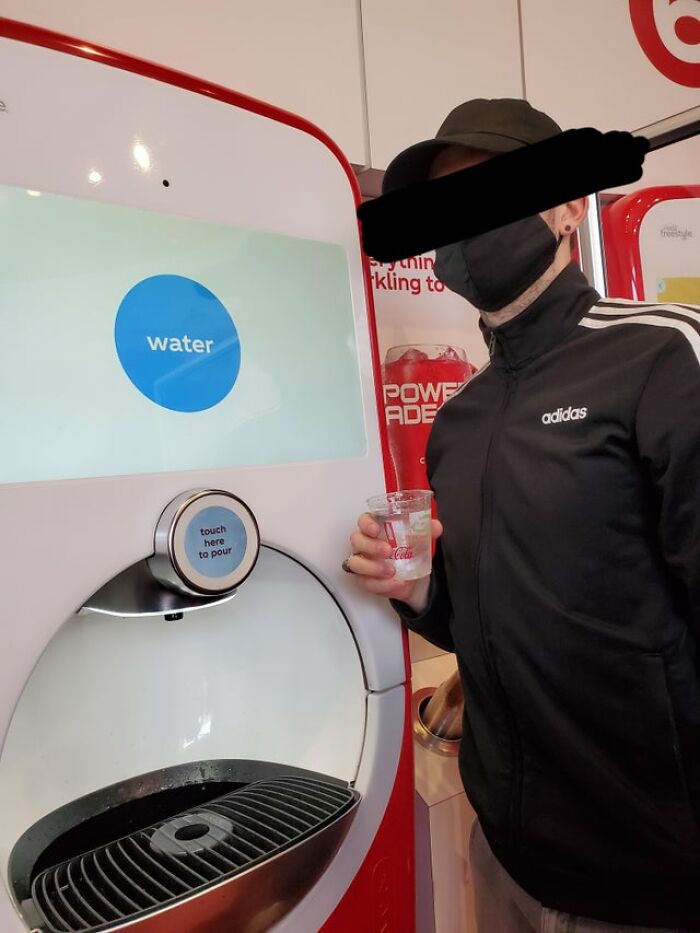 Person in black jacket holding water from a dispenser, highlighting humor around drinking water memes.