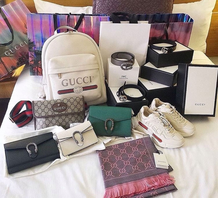 Assorted Gucci luxury bags, shoes, and accessories displayed on a bed, highlighting famous brand sarcastic slogans.