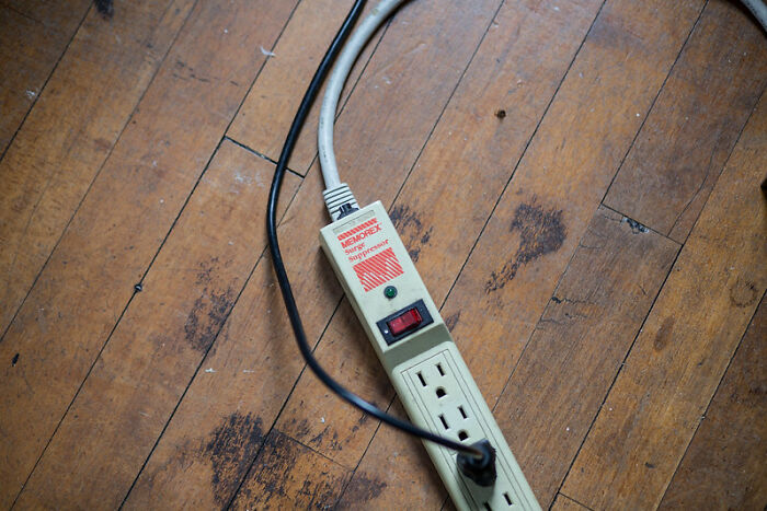 Power strip with surge protector on wooden floor, illustrating a product worth your money from online group recommendations.
