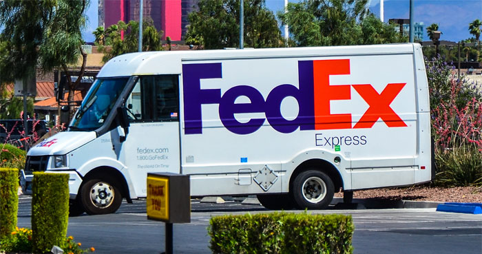 FedEx delivery truck parked outdoors, illustrating sarcastically honest slogans revealing the true nature of famous brands.