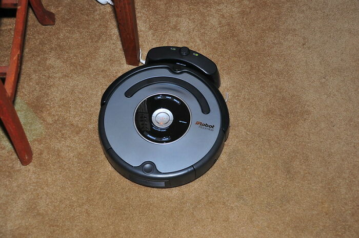 Robot vacuum cleaner on carpet near wooden furniture, a popular product worth the money from online group reviews