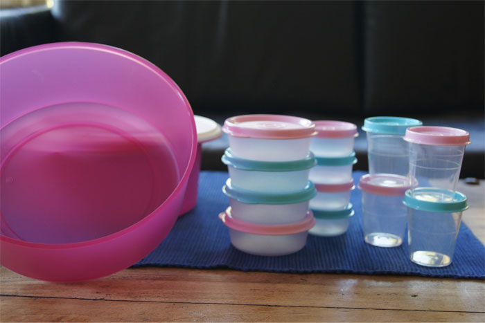 Stacked plastic food containers and bowls on a table showcasing sarcastically honest slogans revealing the true nature of famous brands.