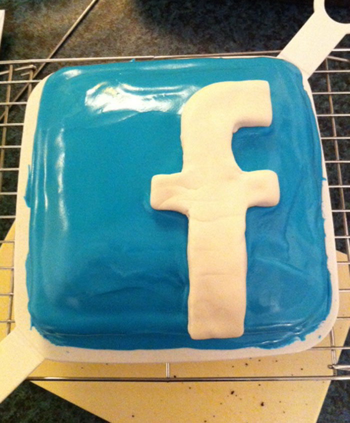 Square cake iced blue with a white Facebook logo, illustrating sarcastically honest slogans about famous brands online.