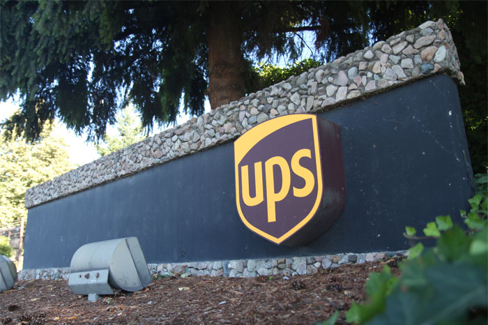 UPS logo on stone wall outdoors, illustrating sarcastically honest slogans revealing the true nature of famous brands.