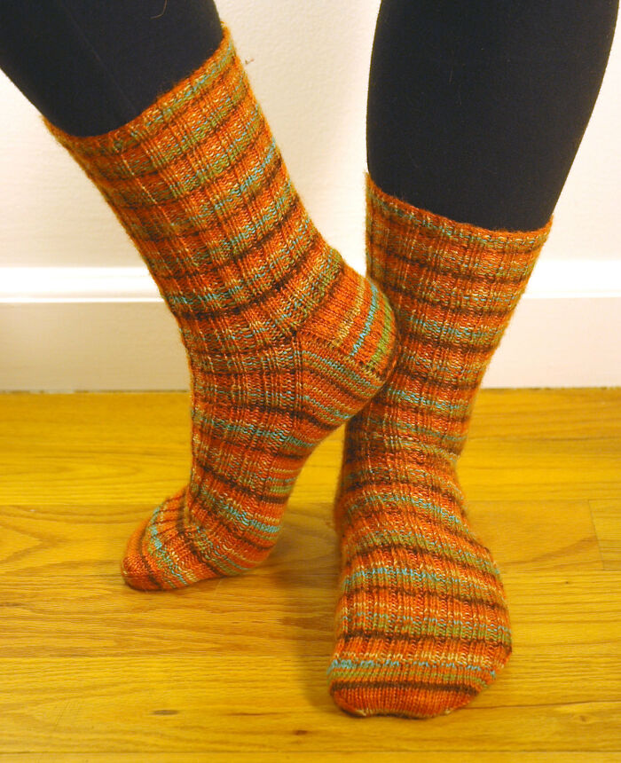 Cozy striped wool socks in warm autumn colors worn on hardwood floor, highlighting comfortable products worth your money.