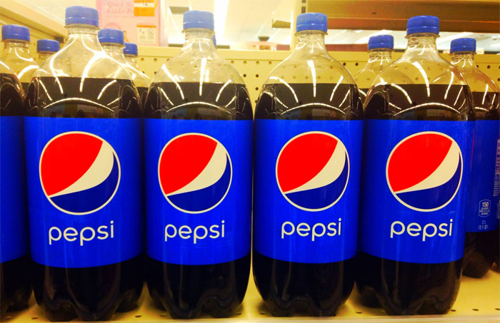 Several bottles of Pepsi lined up on a store shelf representing sarcastically honest slogans about famous brands.
