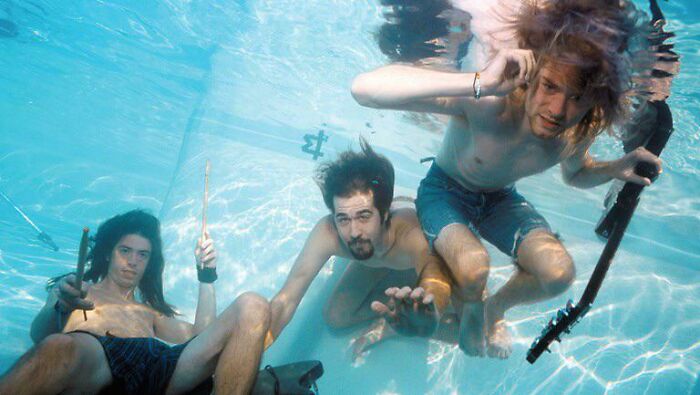 Three people underwater, playing instruments in a unique, historical photo perspective.