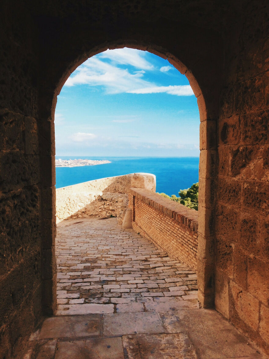Stone archway leading to stunning ocean scenery, capturing beautiful scenery through ancient architecture.
