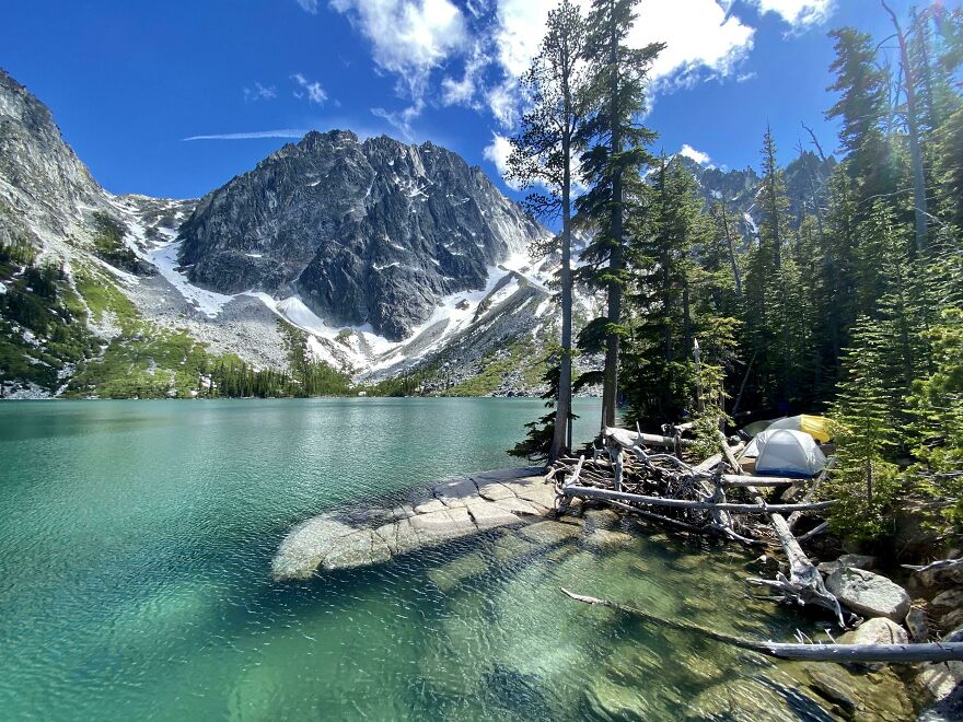 Beautiful scenery of a serene mountain lake surrounded by snow-capped peaks and lush forest.
