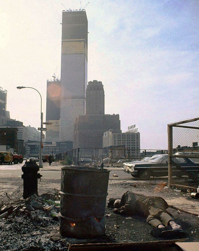 A Homeless Man Sleeps Next To A 50 Gallon Drum Of Burning Scavenged Wood In Front Of The World Trade Center Under Construction, New York City, 1970