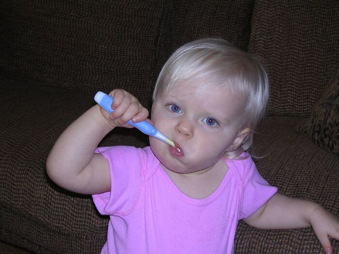 Toddler with blonde hair and blue eyes brushing teeth with a blue toothbrush, highlighting a product worth your money.