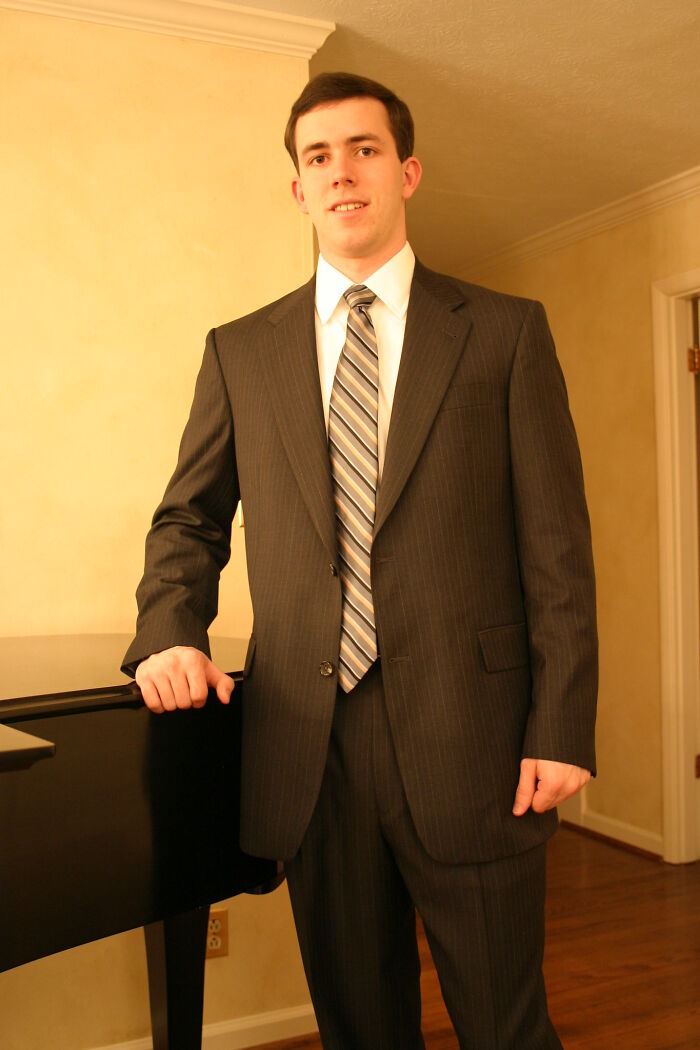 Man in suit standing next to piano indoors, representing online group discussion about products worth money recommendations.