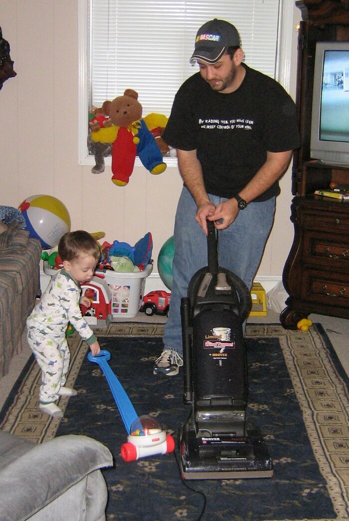 Man and toddler vacuuming and playing indoors surrounded by toys, illustrating product worth and family interaction.