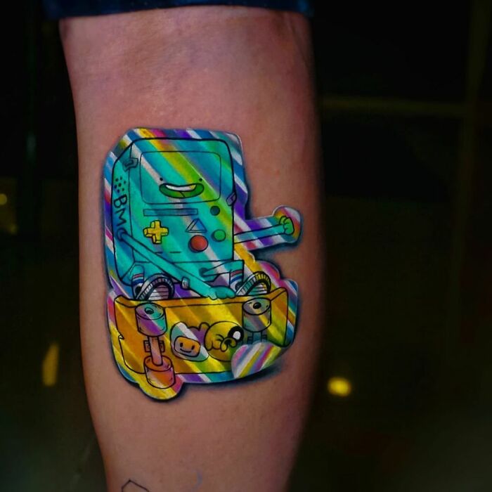 Holographic sticker tattoo on a forearm by Brazilian artist, featuring colorful game console design.
