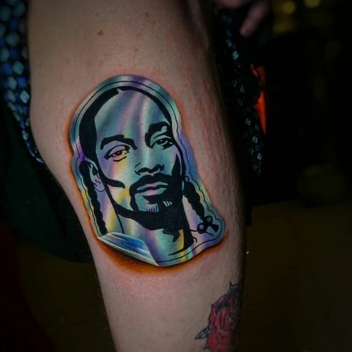 Holographic sticker tattoo on skin, depicting a stylized portrait by a Brazilian artist.